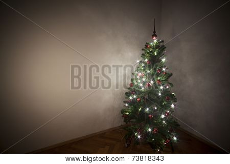 Christmas tree in a dark room with lights turn on.