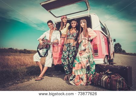 Multi-ethnic hippie friends with guitar on a road trip