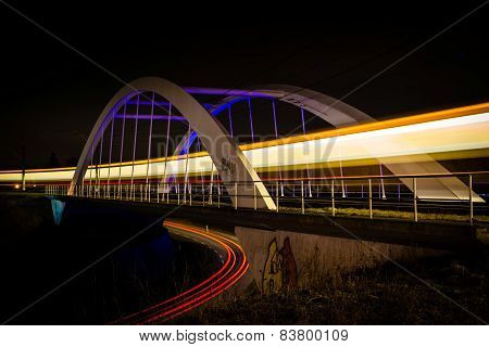 Railway bridge with train and car lights  at night