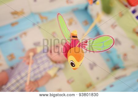Bee Hanging Above The Bed. Kid Laying In The Backgorund