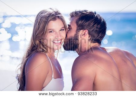 Handsome man receiving kiss from his gilfriend at the beach