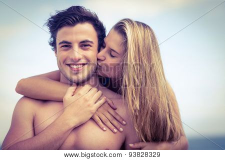 Handsome man receiving kiss from his gilfriend at the beach
