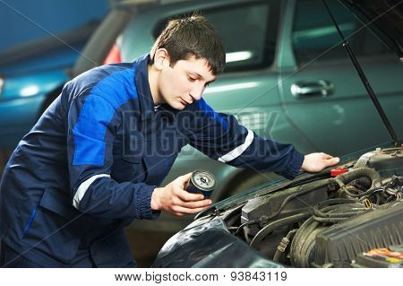 Car servicing, oil and filter replacing maintenace. Selective focus on mechanic face