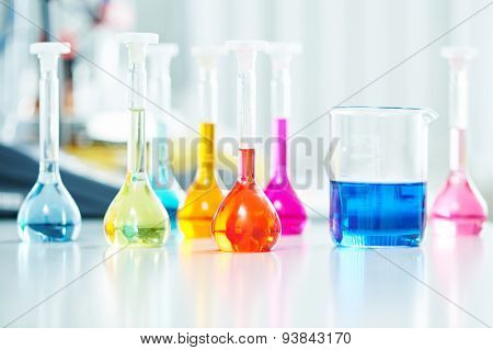 Pharmacy and chemistry theme. Test glass flask with solution in research laboratory. Shallow DOF. Focus on red bottle.