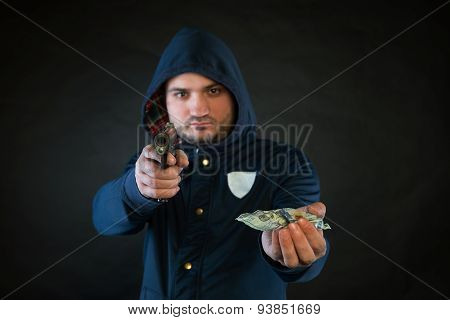 A Person In A Hoodie Is Aiming And Holding The Other Hand With The Dollar Note. A Concept Of The Rob