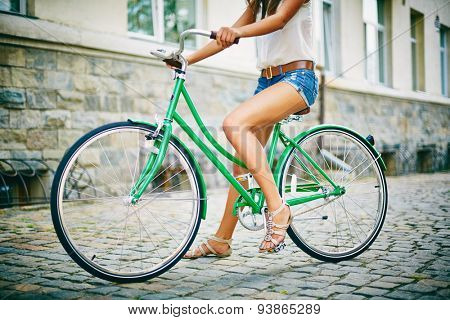 Legs of pretty girl sitting on bicycle in urban environment