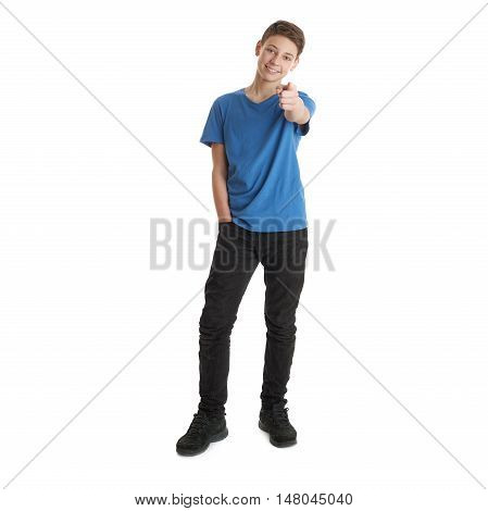 Cute teenager boy in blue T-shirt standing and poinitng forward over white isolated background full body