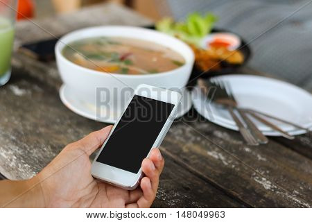 Woman use mobile phone in coffee shop view from backside and meal background.