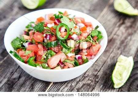 Delicious, spicy sauce Pico de Gallo also called salsa Fresca. Traditional recipe, fresh tomatoes, red onion, cilantro, lime juice and spicy jalapenos. National Mexican cuisine. Wood rustic background