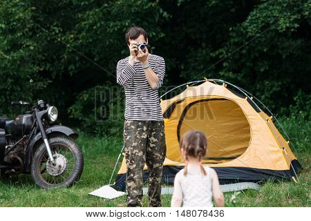 Father taking photo of his daughter in forest. Summer week-end outdoors, family trip