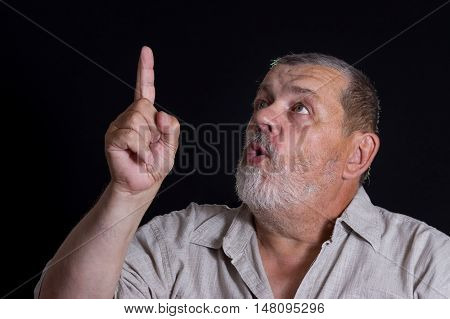 Very emotional portrait of senior man pointing forefinger up