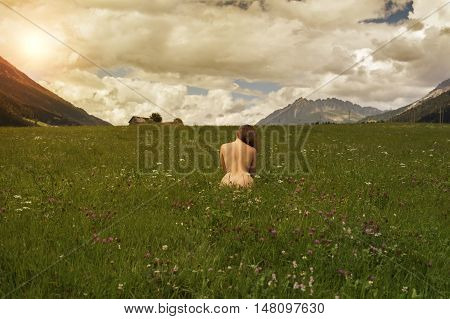 Naked female in a field at sunset