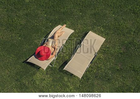 woman lying on a sunbed with book