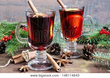 christmas mulled wine with cinnamon sticks anise and orange on wooden table background with fir branches and pine cones