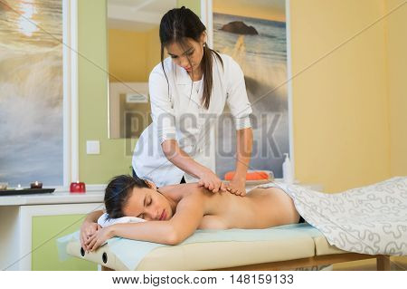 Young woman enjoying back massage in beauty spa salon.