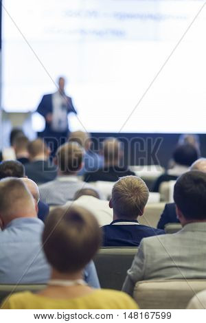 Business Ideas and Concepts. People at the Business Conference Listening to the Speaker Standing in Front of a Big Board on Stage.Vertical Image Orientation