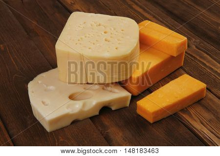 various types of fresh raw aged delicatessen cheese on wooden table cheddar edam swiss