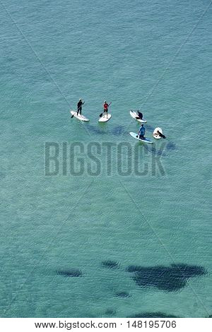 Five board riders having a conversation whilst sitting in deep water