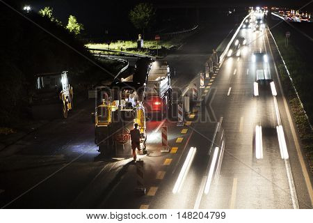 Wallau, Germany - September 16, 2016: High angle view of construction site on German highway A66 at night some workers in the foreground - long exposure