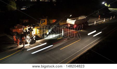 Wallau, Germany - September 16, 2016: High angle view of construction site on German highway A66 at night some workers in the foreground - long exposure