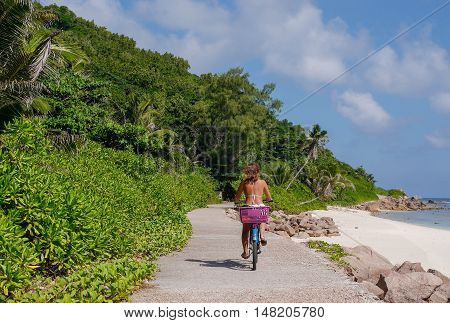 A girl in a swimsuit on the bike on La Digue. Tropical Seychelles