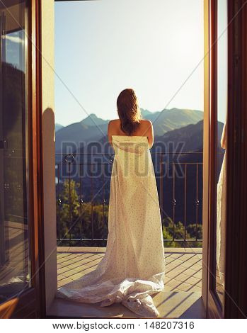 Female standing on the balcony in a sheet