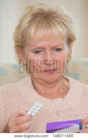 Concerned Senior Woman Reading Information On Medicine Packet