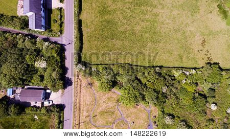 An aerial view of a country road with solitary houses on one sode and empty landscape on the other.