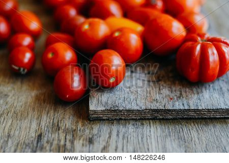 Tomato on wooden table. Freshly Picked red Tomatoes. Variation of tomatoes on wooden surface. Vegetables in the section. Harvesting. Healthy food from the garden.