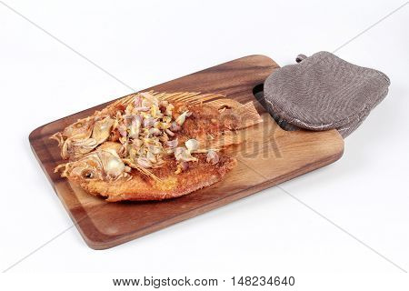 Deep fried fish ,Nile tiapia, with crispy garlic on butcher served isolated white background. Side view.