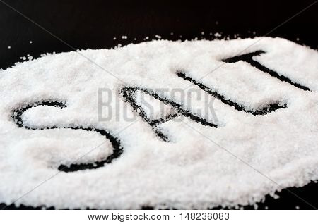 Word from the sea of scattered salt on a black table. Sea salt on a black background