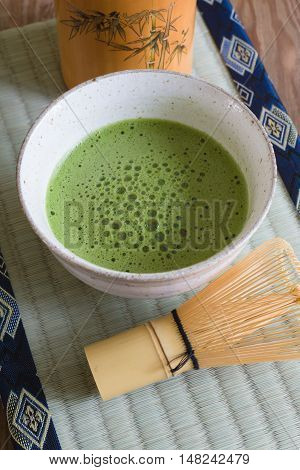 Japanese Matcha green tea in a chawan or traditional ceramic bowl with a tatami mat background