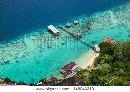 View of jetty at Bohey Dulang,Tun Sakaran Marine Park  island Semporna,Sabah.Mirror smooth ocean surrounded by mountains.The bright blue water and rocky shore in the tropical island of Semporna,Borneo