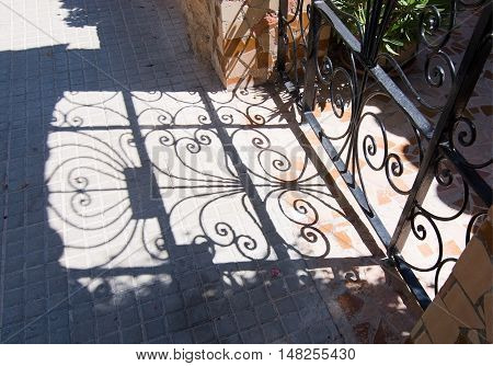 CALA FORNELLS MALLORCA SPAIN - SEPTEMBER 6 2016: Beautiful shadow play from wrought iron fence on a sunny day on September 6 2016 in Cala Fornells Mallorca Spain.