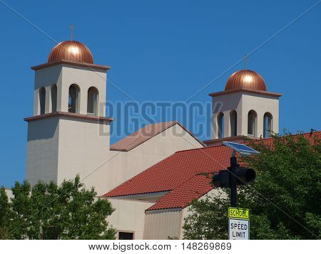 The twin bell towers of a large Spanish Mission type architecture Catholic church coated the domes so that they will never turn green. The main dome over the cruciform and the apse dome are also coated but much larger in scale.