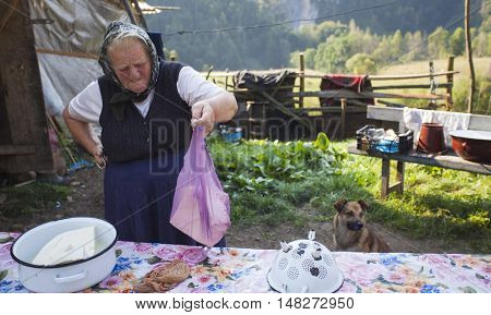 Salciua, Romania - September 14, 2016: Old rural woman selling cheese at the farm in the mountains