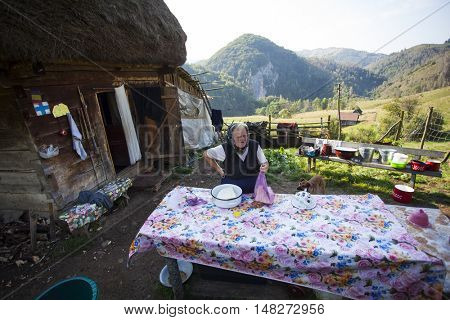 Salciua, Romania - September 14, 2016: Old rural woman selling cheese at the farm in the mountains