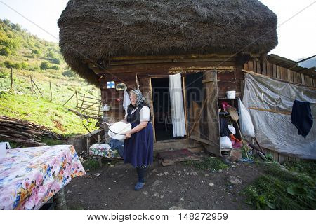 Salciua, Romania - September 14, 2016: Old rural woman selling cheese at the farm in the mountains