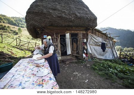 Salciua, Romania - September 14, 2016: Old rural woman selling cheese at the farm in the mountains