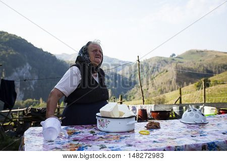 Salciua, Romania - September 14, 2016: Old rural woman selling cheese at the farm in the mountains