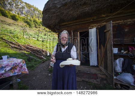 Salciua, Romania - September 14, 2016: Old rural woman selling cheese at the farm in the mountains