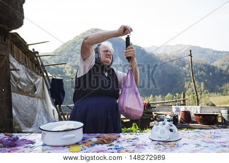Salciua, Romania - September 14, 2016: Old rural woman selling cheese at the farm in the mountains