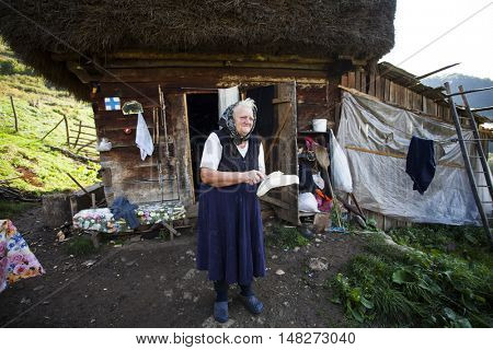 Salciua, Romania - September 14, 2016: Old rural woman selling cheese at the farm in the mountains