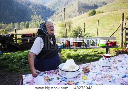 Salciua, Romania - September 14, 2016: Old rural woman selling cheese at the farm in the mountains