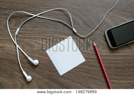 White Headphone, Paper, Phone And Pencil On Wooden Table