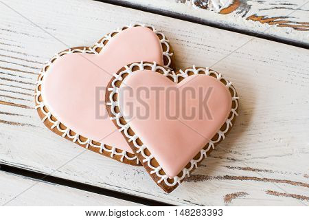 Pair of heart-shaped biscuits. Light pink icing on cookies. Unforgettable taste of love. Small delicious gift.