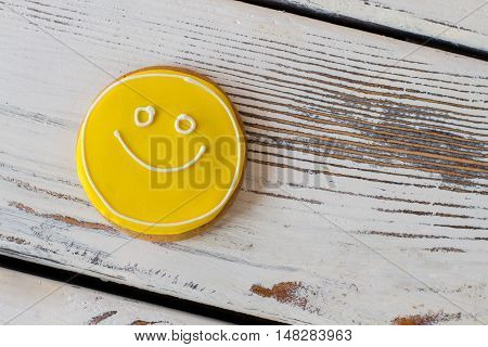 Smiley biscuit on wooden background. Round cookie with glaze. Simplest recipe of great mood. Dessert charges you with energy.