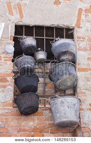 old pots and pans hanging on window of farm