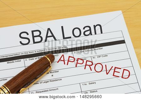 Applying for a SBA Loan Approved SBA Loan application form with a pen on a desk with an approved stamp