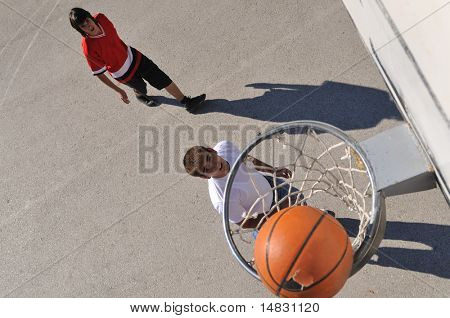 gorup de rapazes que jogar basquete ao ar livre na rua, com longas sombras e bird Ver os psicoló